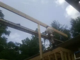 Carpenter setting a ridge beam over a new addition frame — Ice Dam Removal by Roofing Brothers in Harrells