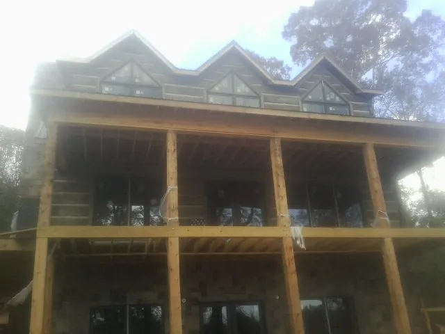 Dormers and porch framing on a large log home under construction — Roof Coating work by our crew in Harrells
