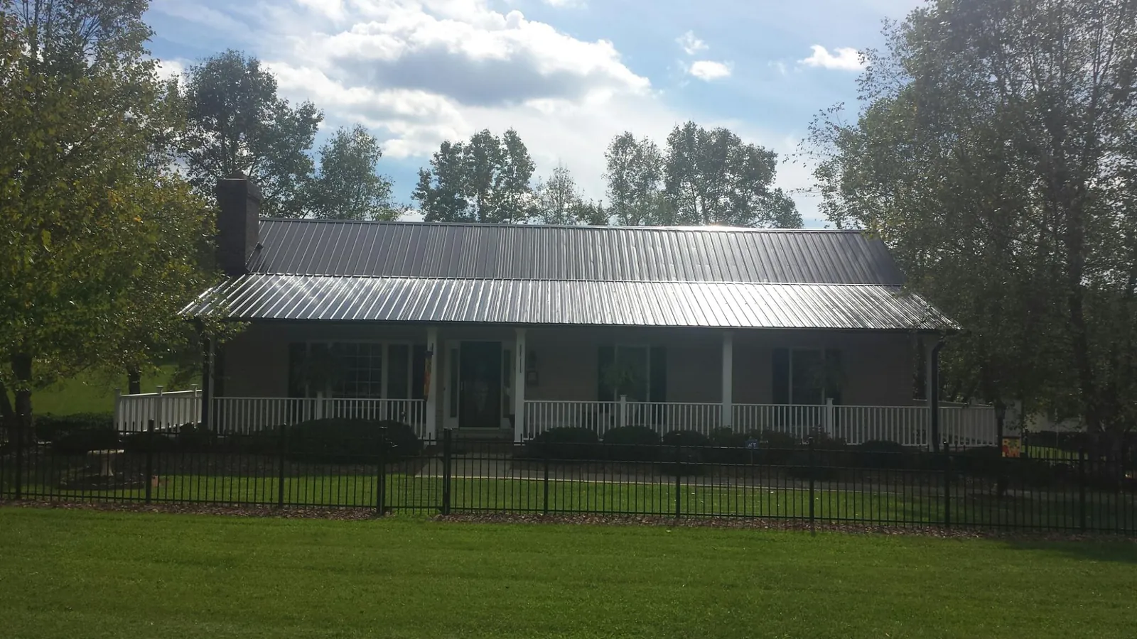 Gray metal roof on a brick ranch with a full width front porch — Gutter Guard Installation work by our crew in Harrells