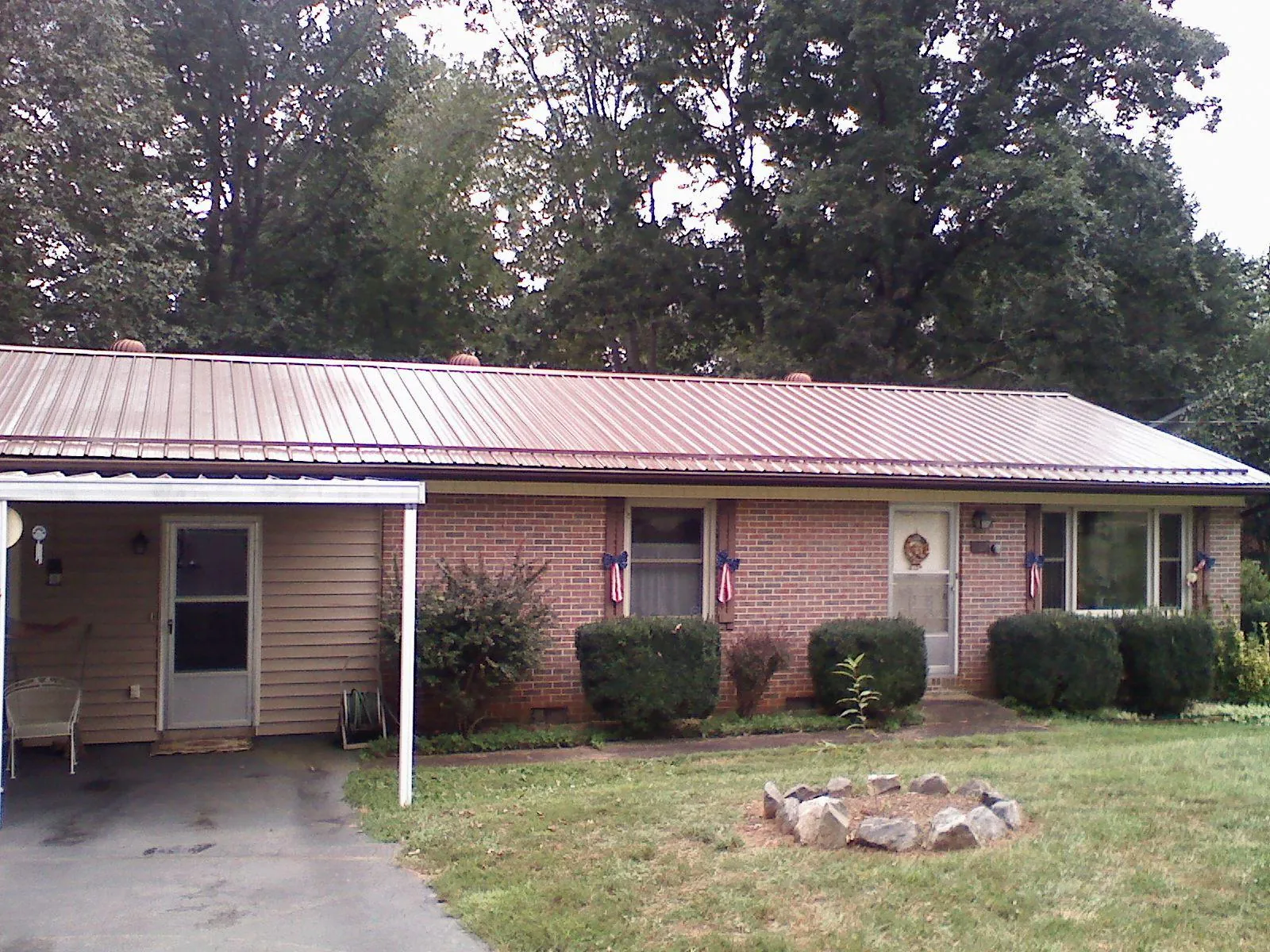 Bronze metal roof and carport on a brick ranch home — Roof Repair work by our crew in Harrells